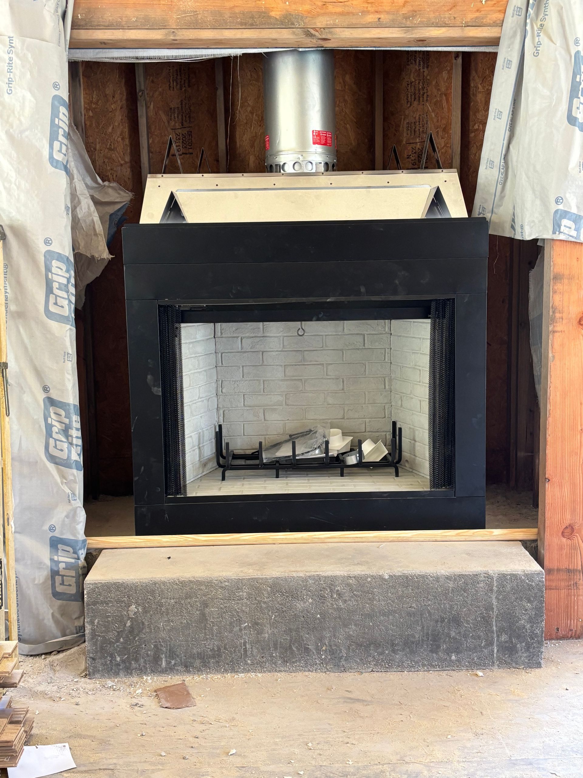 Black fireplace frame with white brick interior, gray hearth, and silver flue.