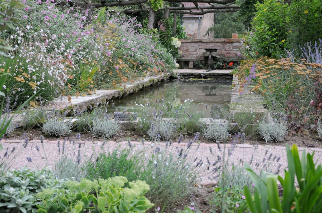Das Wasserbecken im Sommer, begleitet von Schafgarbe (Achillea x filipendula ,Walter Funcke') und Prachtkerze (Gaura lindheimeri).