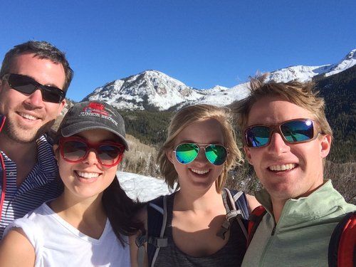 A group of people wearing sunglasses are posing for a picture with mountains in the background.