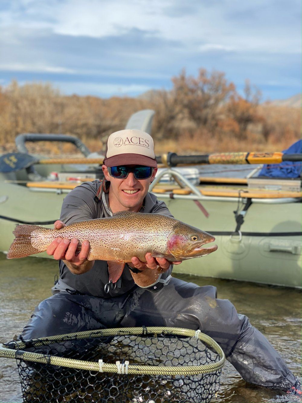 A man is holding a rainbow trout in a net.