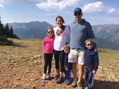 A family is posing for a picture on top of a mountain.
