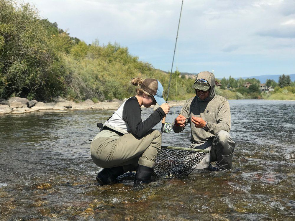 A man and a woman are fishing in a river.
