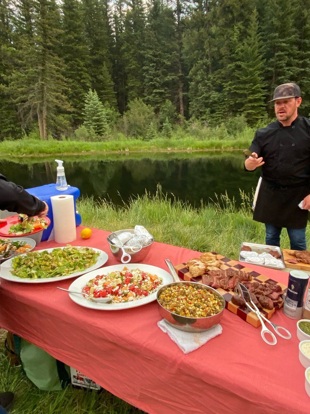 A man is standing next to a table with plates of food on it.