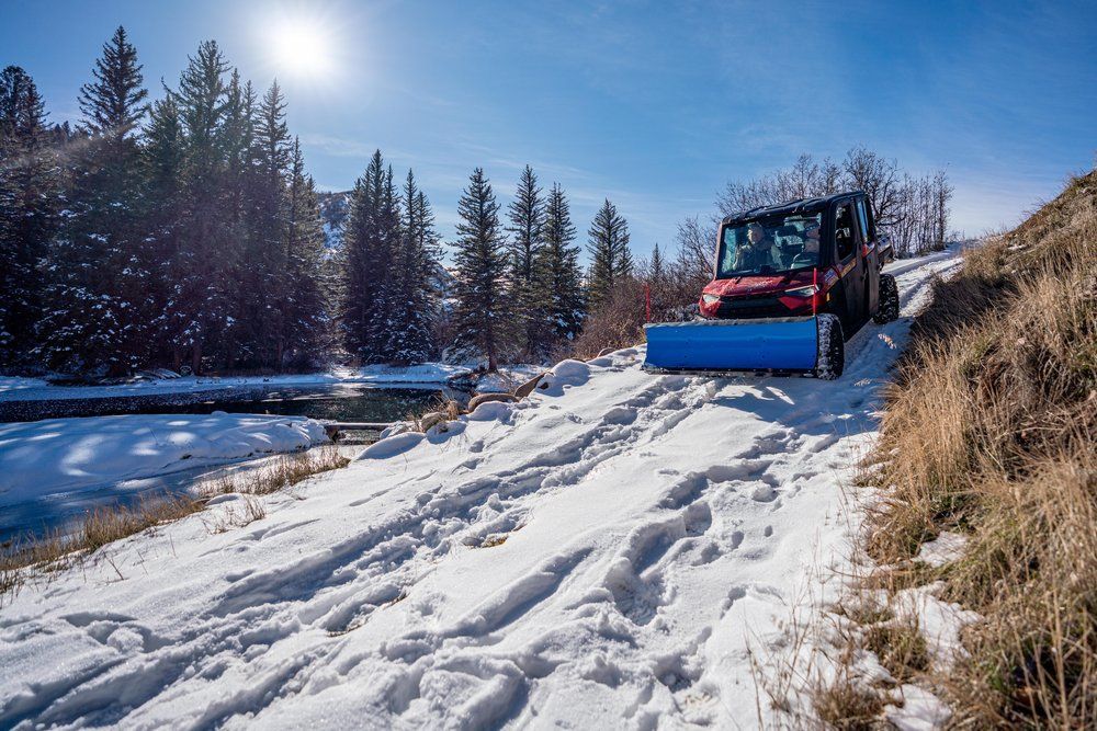 A snow plow is driving down a snow covered road.