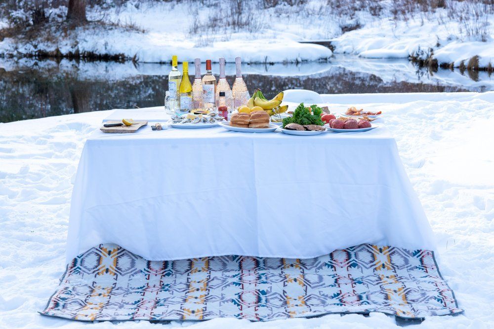 A table with food and drinks on it in the snow.
