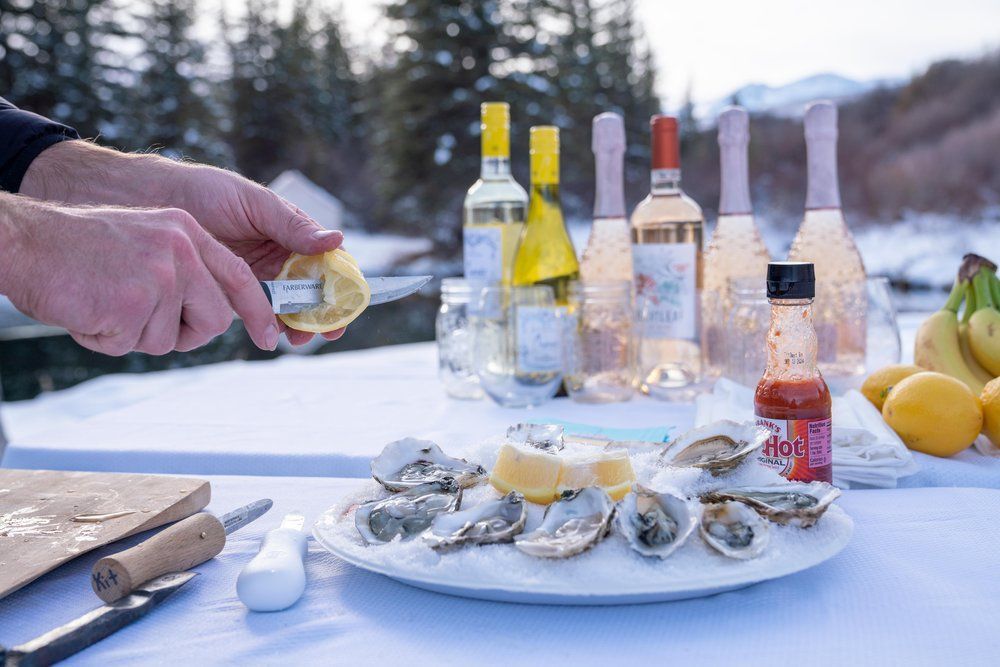 A person is cutting an oyster on a plate on a table.