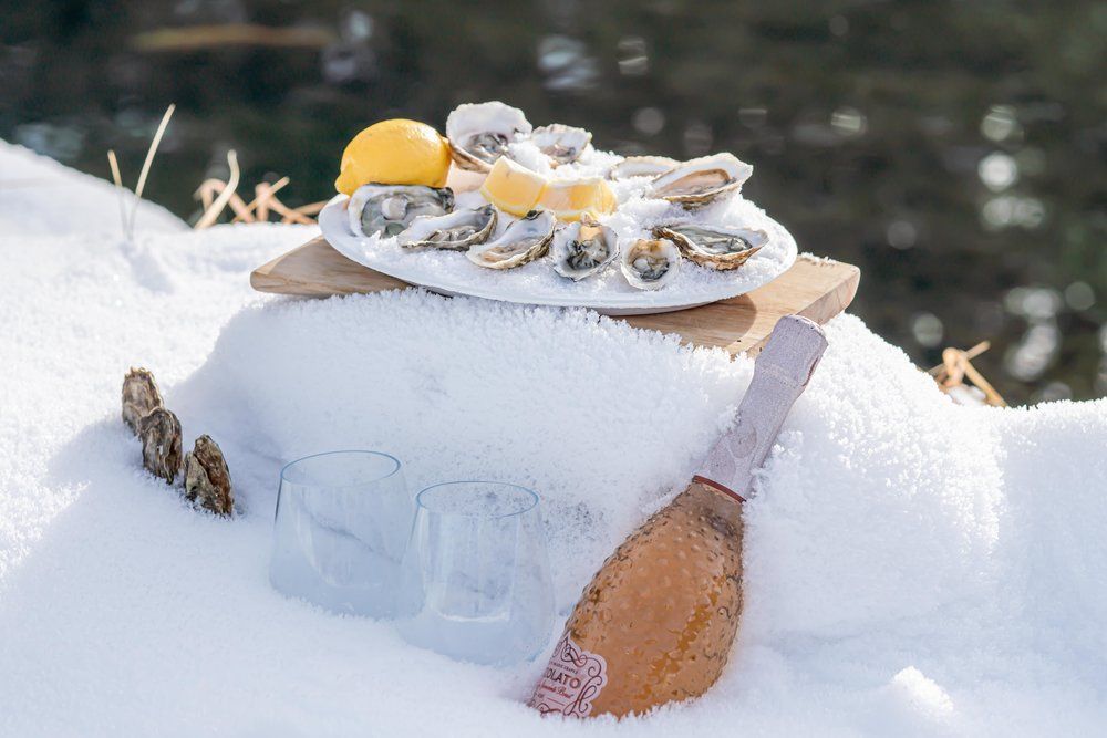 A plate of oysters and a lemon on a cutting board in the snow.