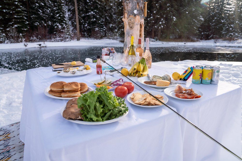 A table with plates of food and drinks on it in the snow.