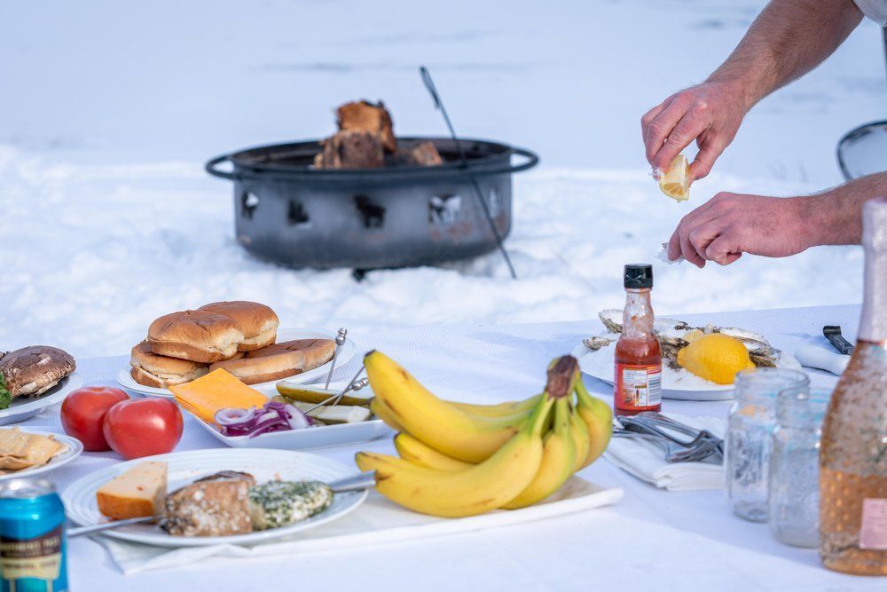 A person is preparing food on a table in the snow.