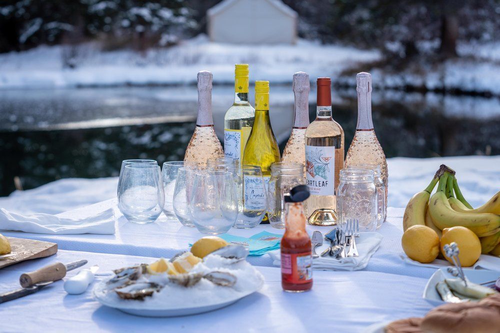 A table with bottles of wine , bananas , lemons and oysters on it.