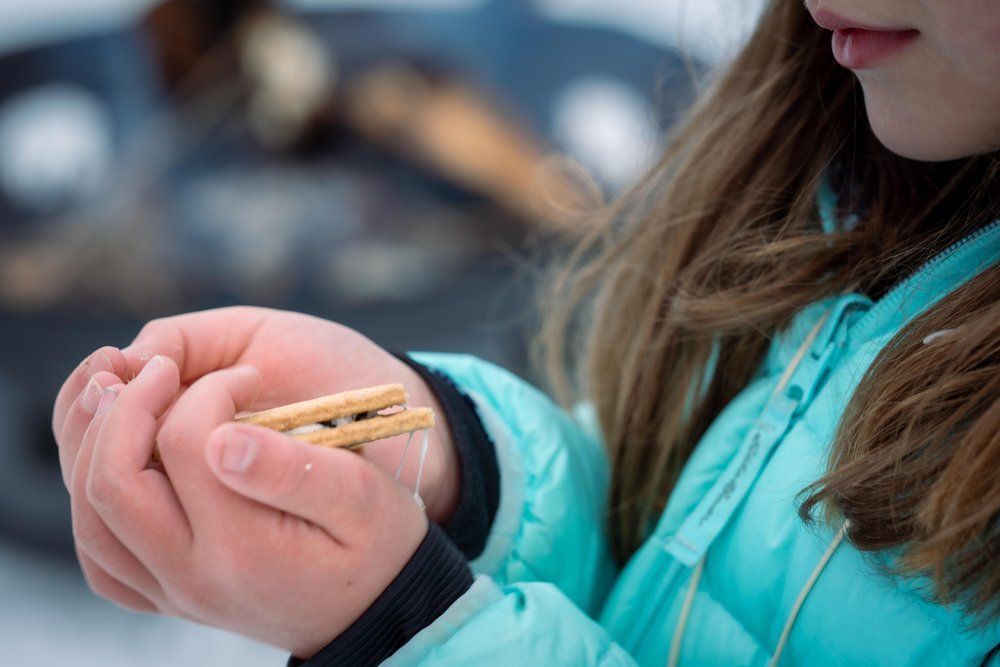 A young girl is holding a cookie in her hands in the snow.