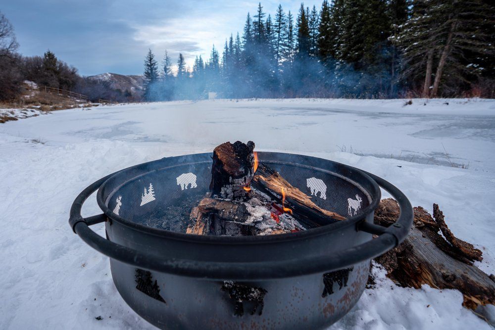 A fire pit is sitting in the middle of a snow covered field.
