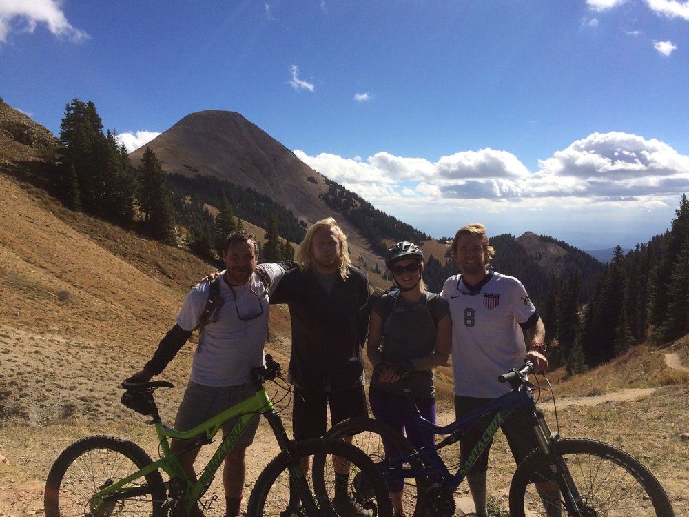 A group of people are posing for a picture with their bikes in front of a mountain.