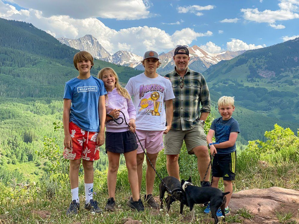 A group of people standing next to each other on top of a hill with mountains in the background.