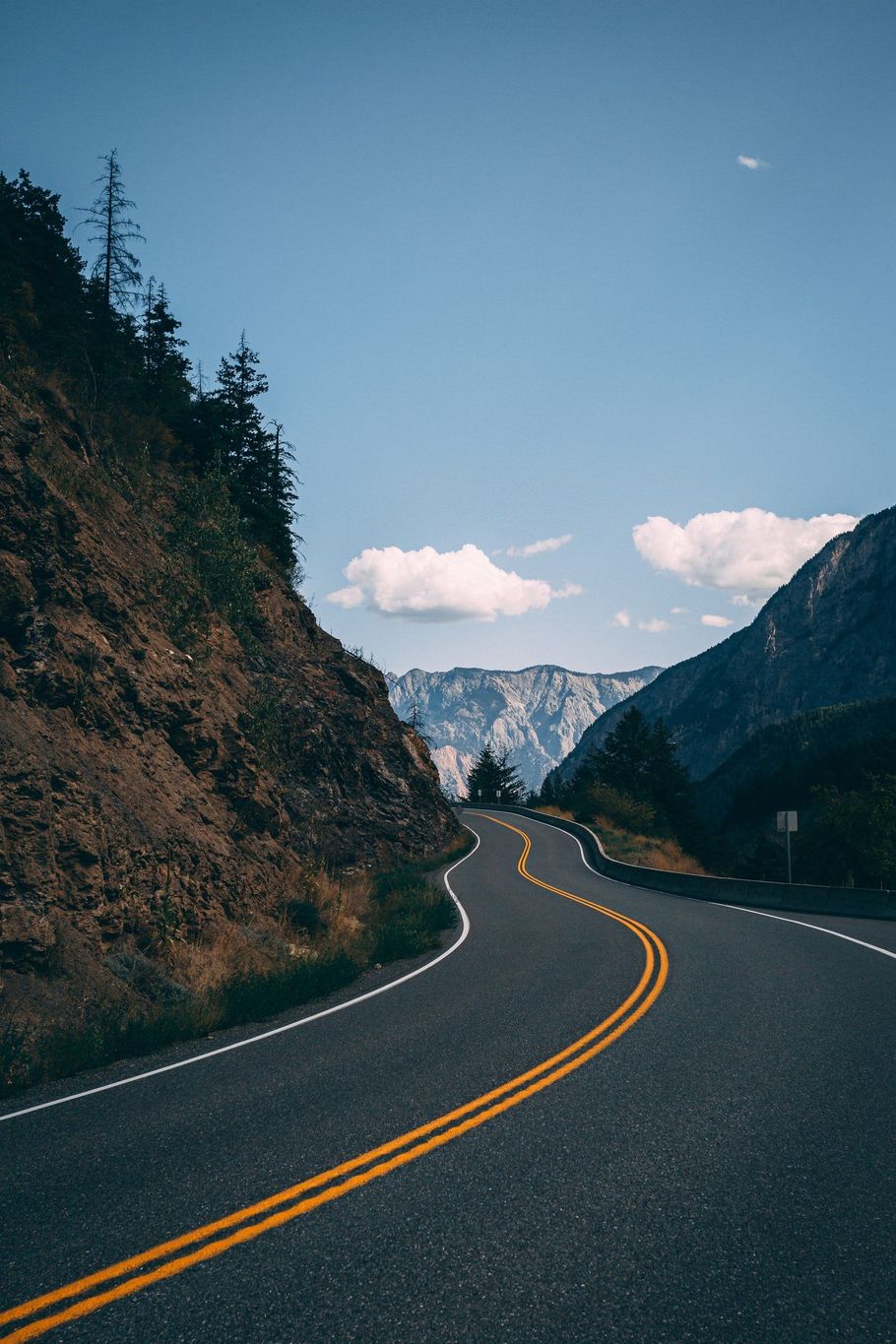 A road going through a mountainous area with mountains in the background.