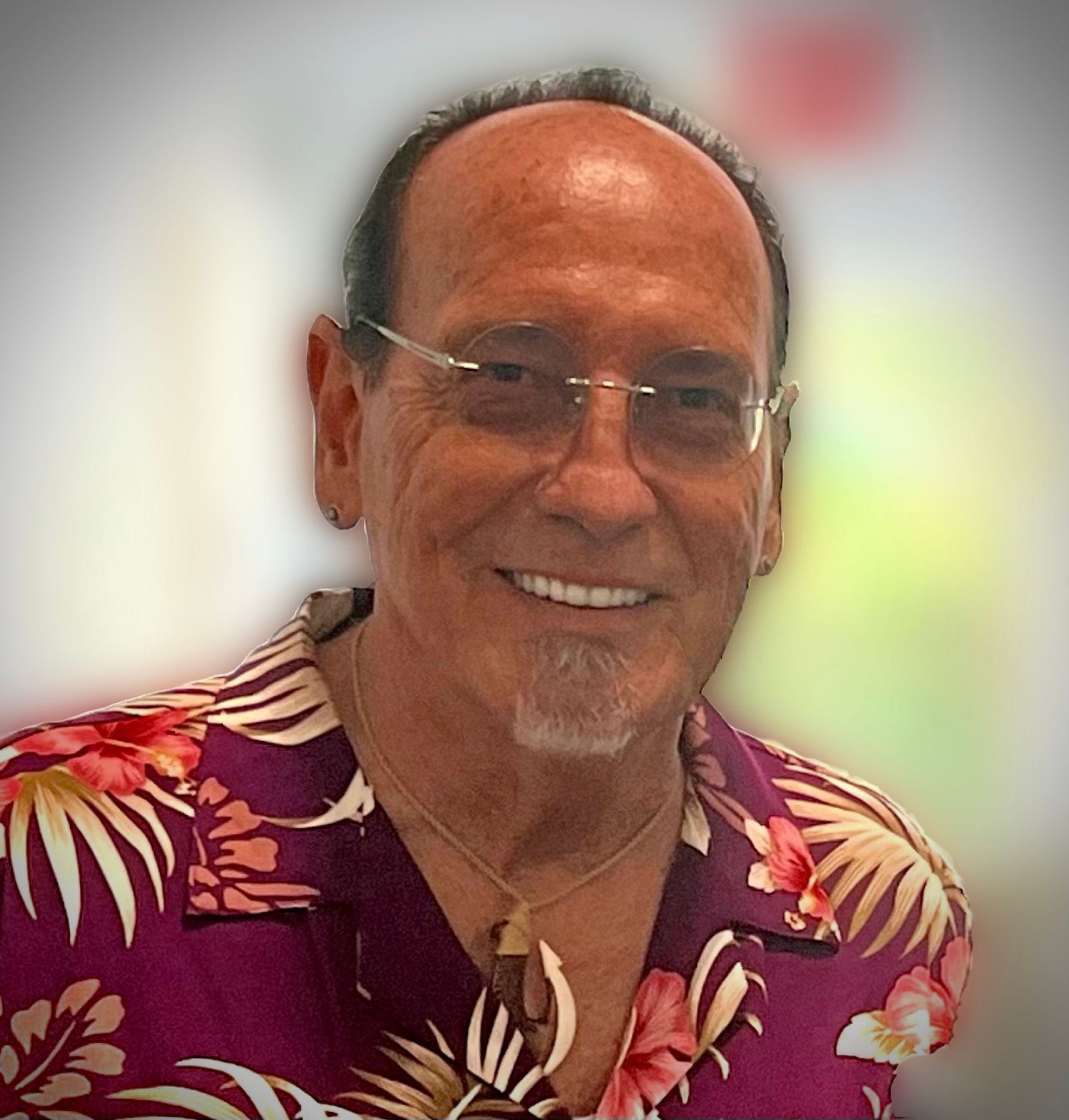 A man wearing glasses and a hawaiian shirt smiles for the camera