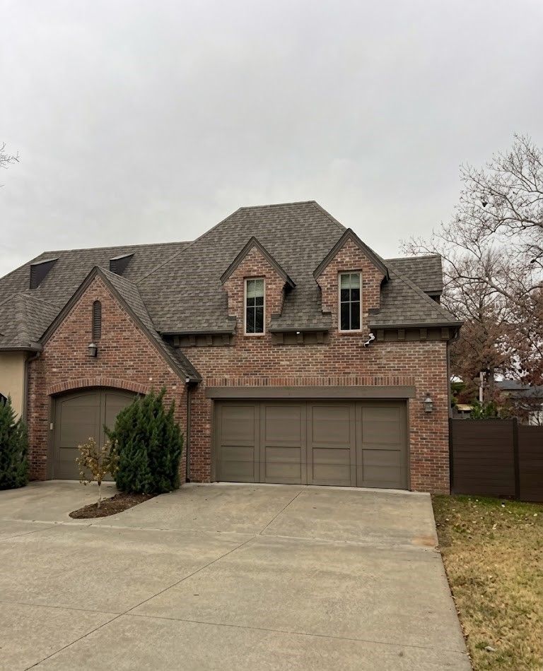 Brick suburban house with attached garage and concrete driveway under an overcast sky