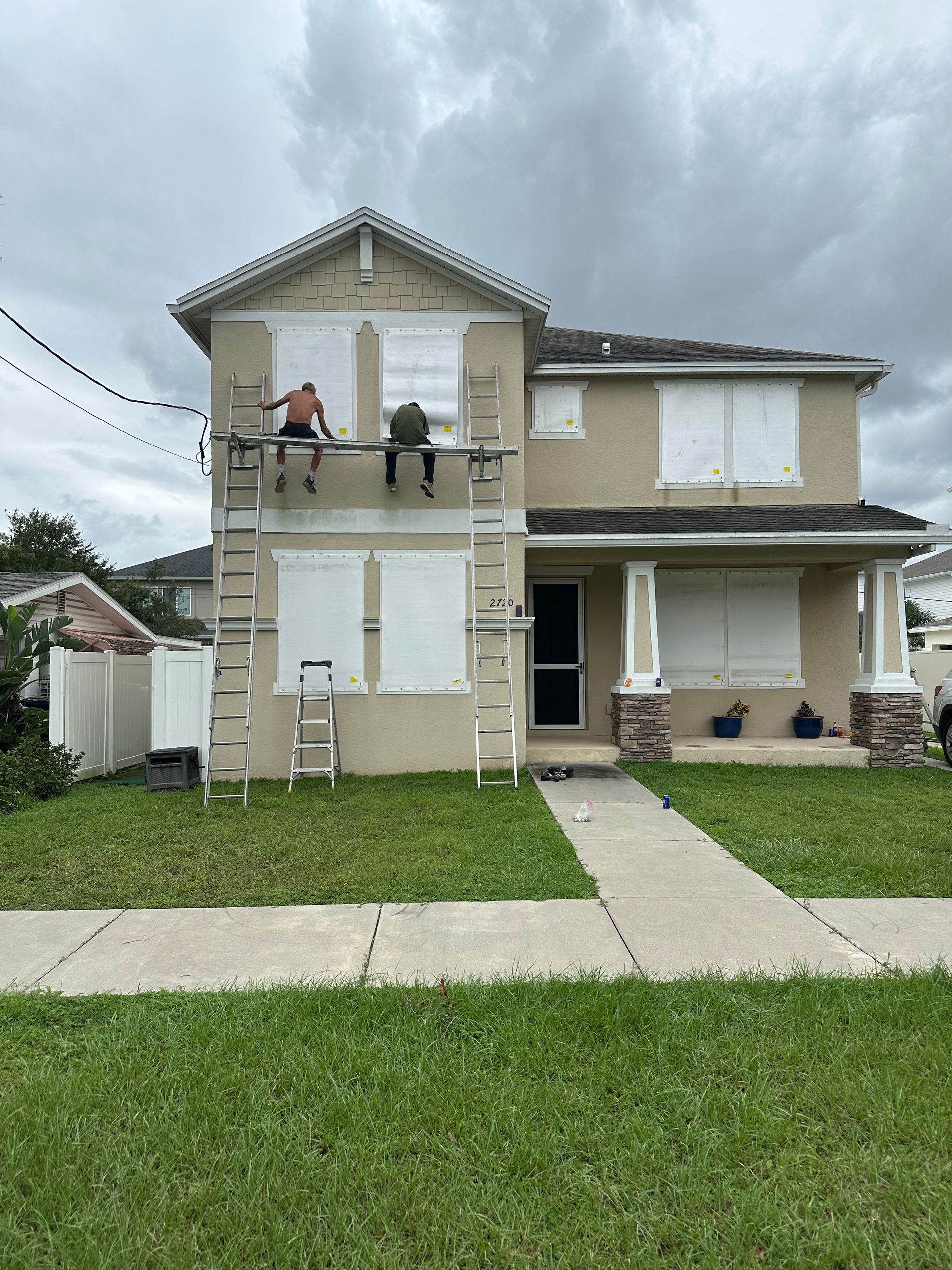 A man is sitting on a ladder on the side of a house.