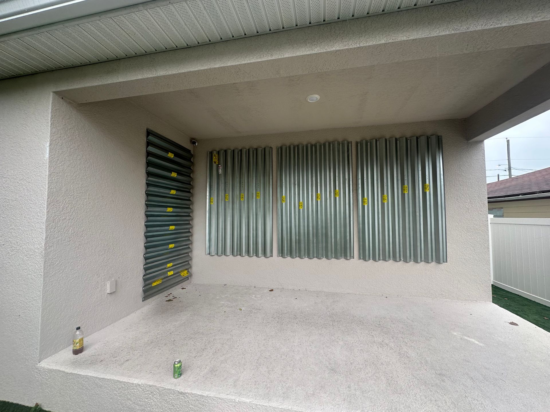 There is a bottle of soda on the ground in front of a house.