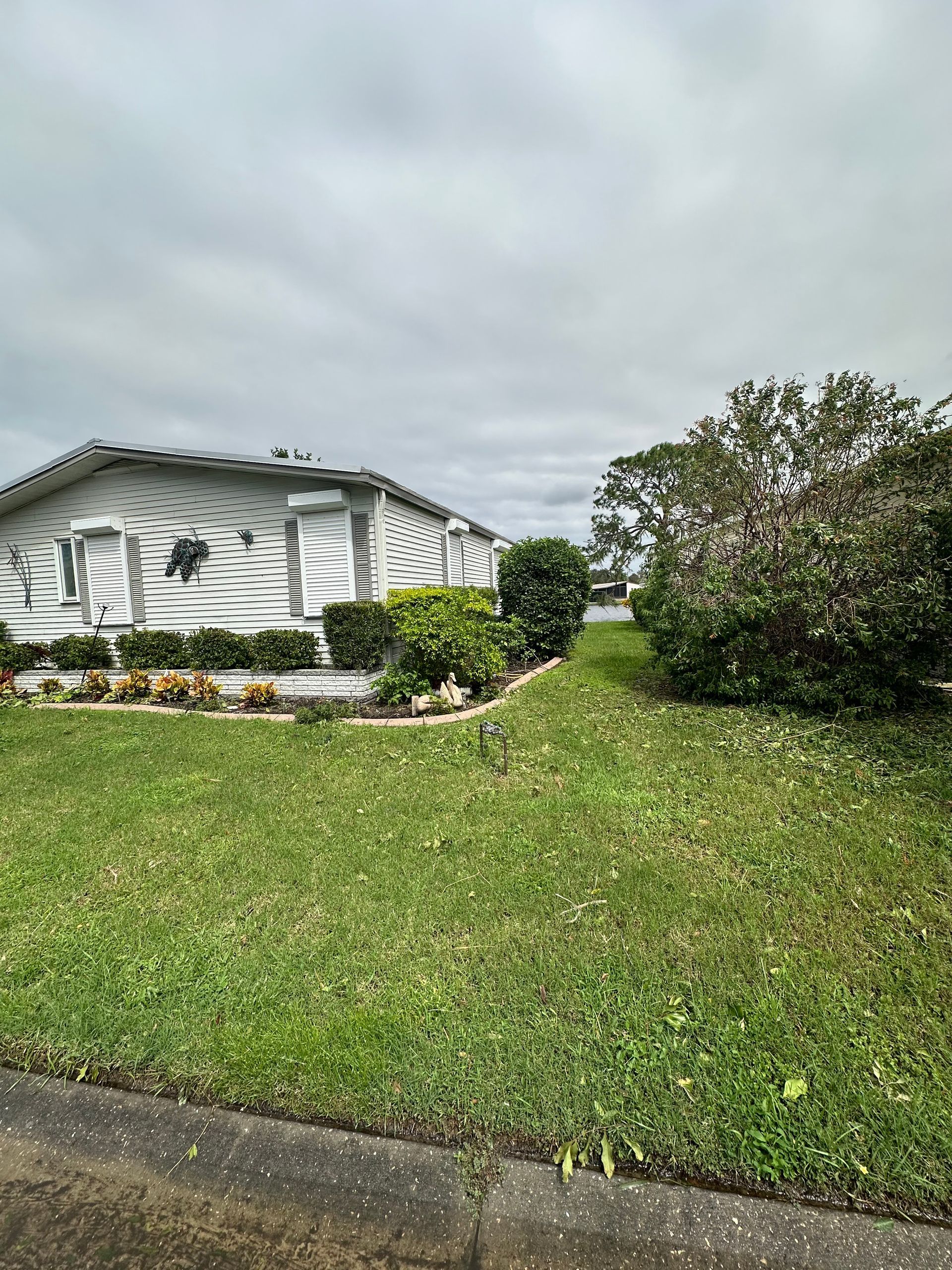 A white mobile home with a lush green lawn in front of it.