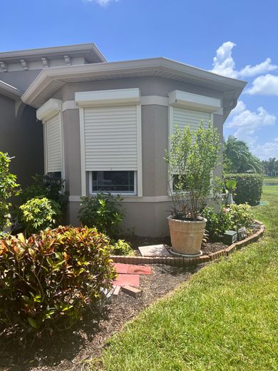 A white building with three windows and shutters on it
