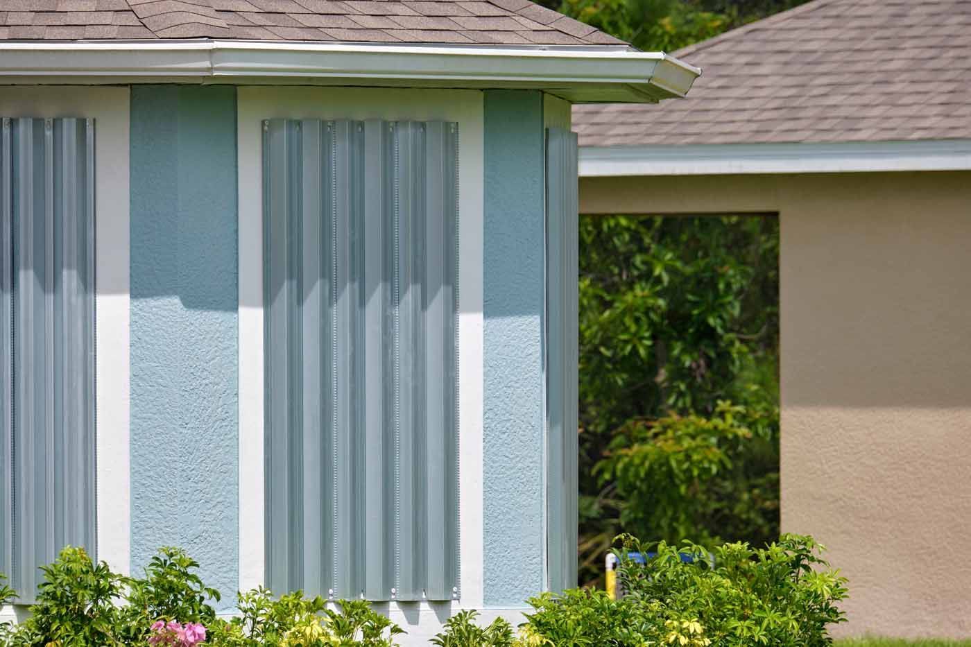 A blue and white house with vertical blinds on the windows