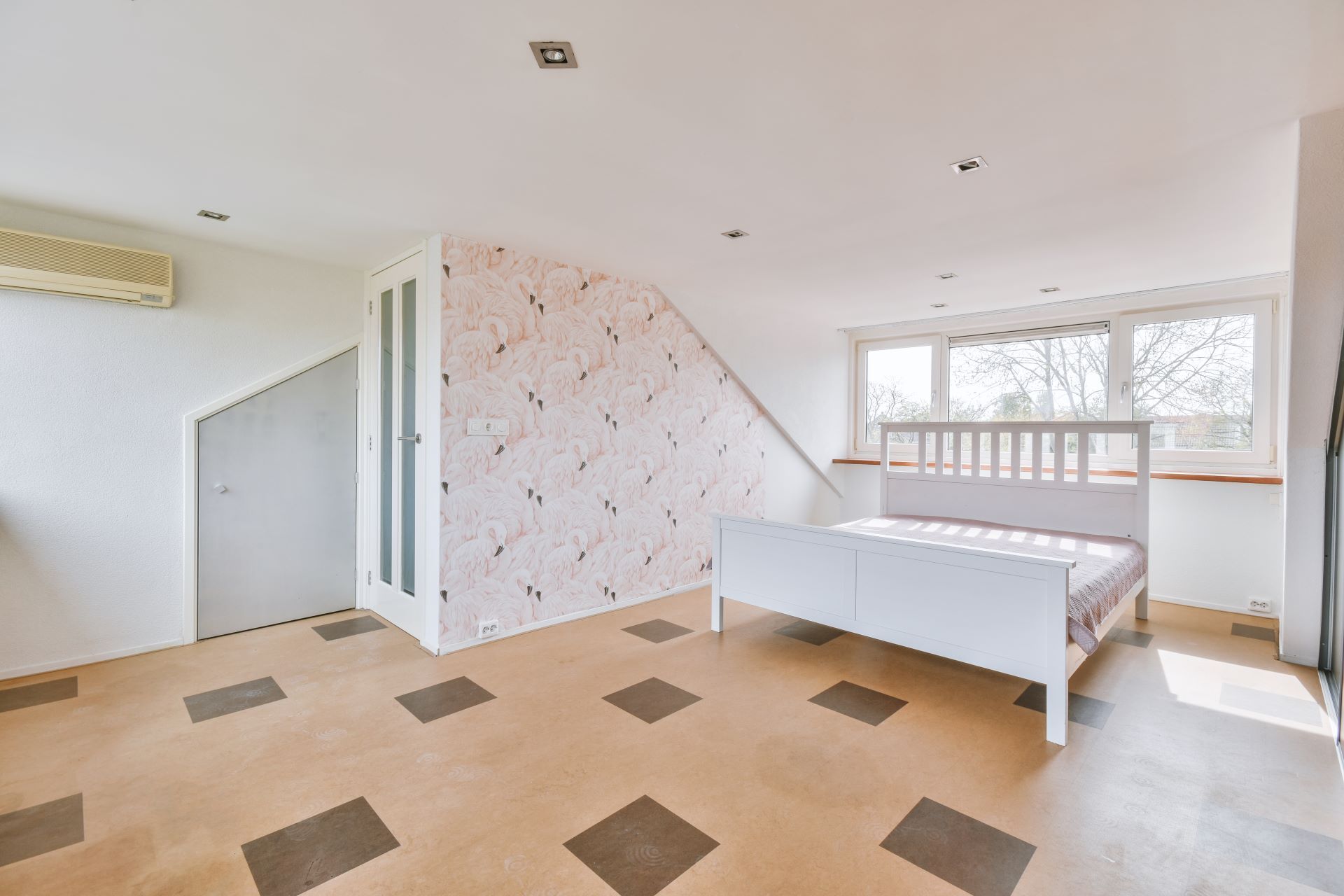 Bedroom with white bed, slanted wall with pattern, and a window.