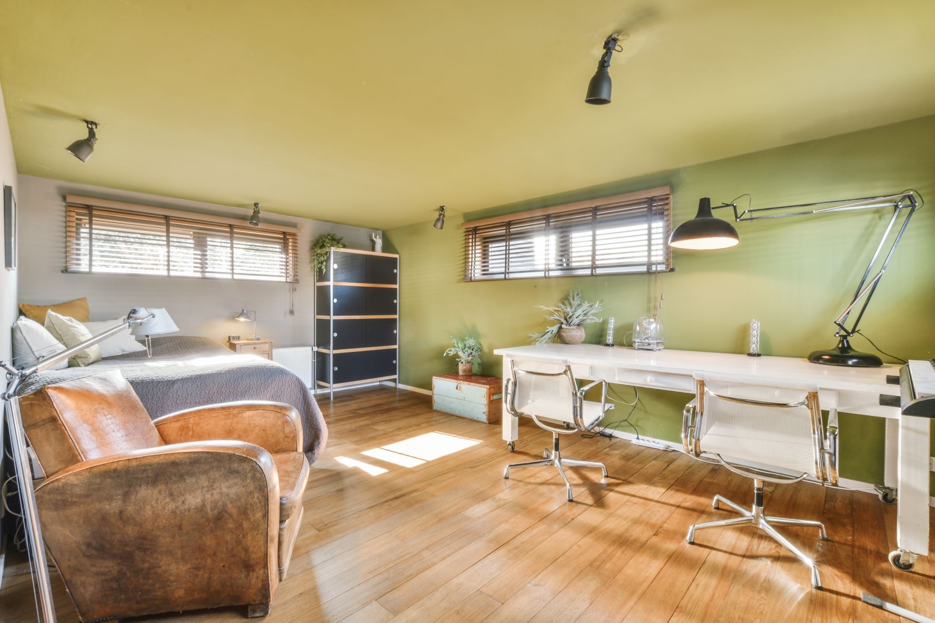 Bedroom with desk, bed, and armchair; green and wood tones dominate.
