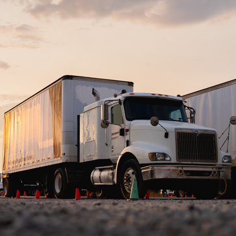 A white semi truck with a trailer is parked on the side of the road.