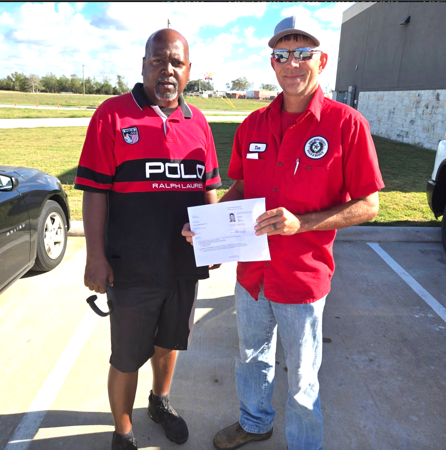 Two men in red polo shirts are standing next to each other