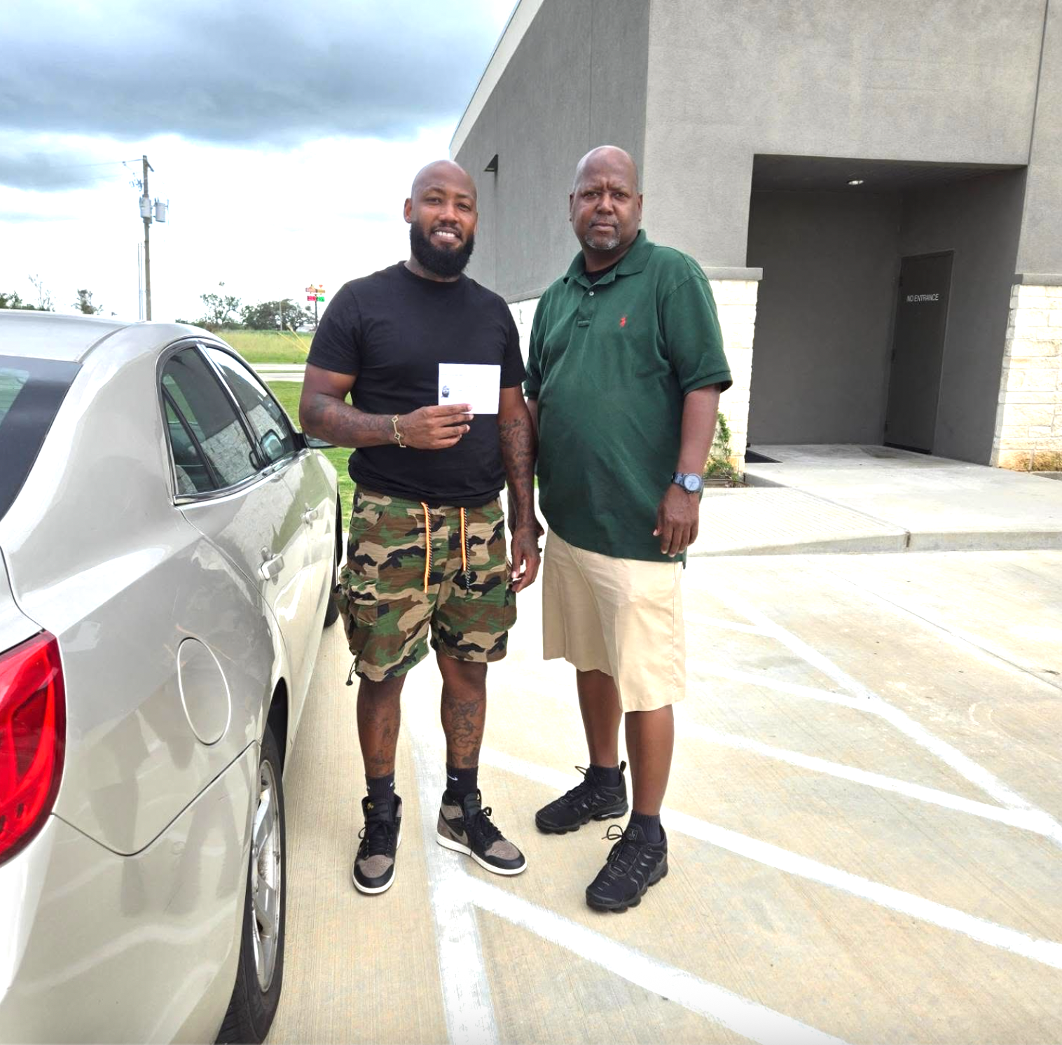 Two men standing next to a car in a parking lot