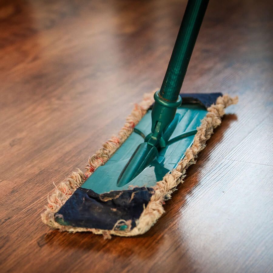 Mop cleaning a wooden floor, green handle, blue mop head, close-up shot.