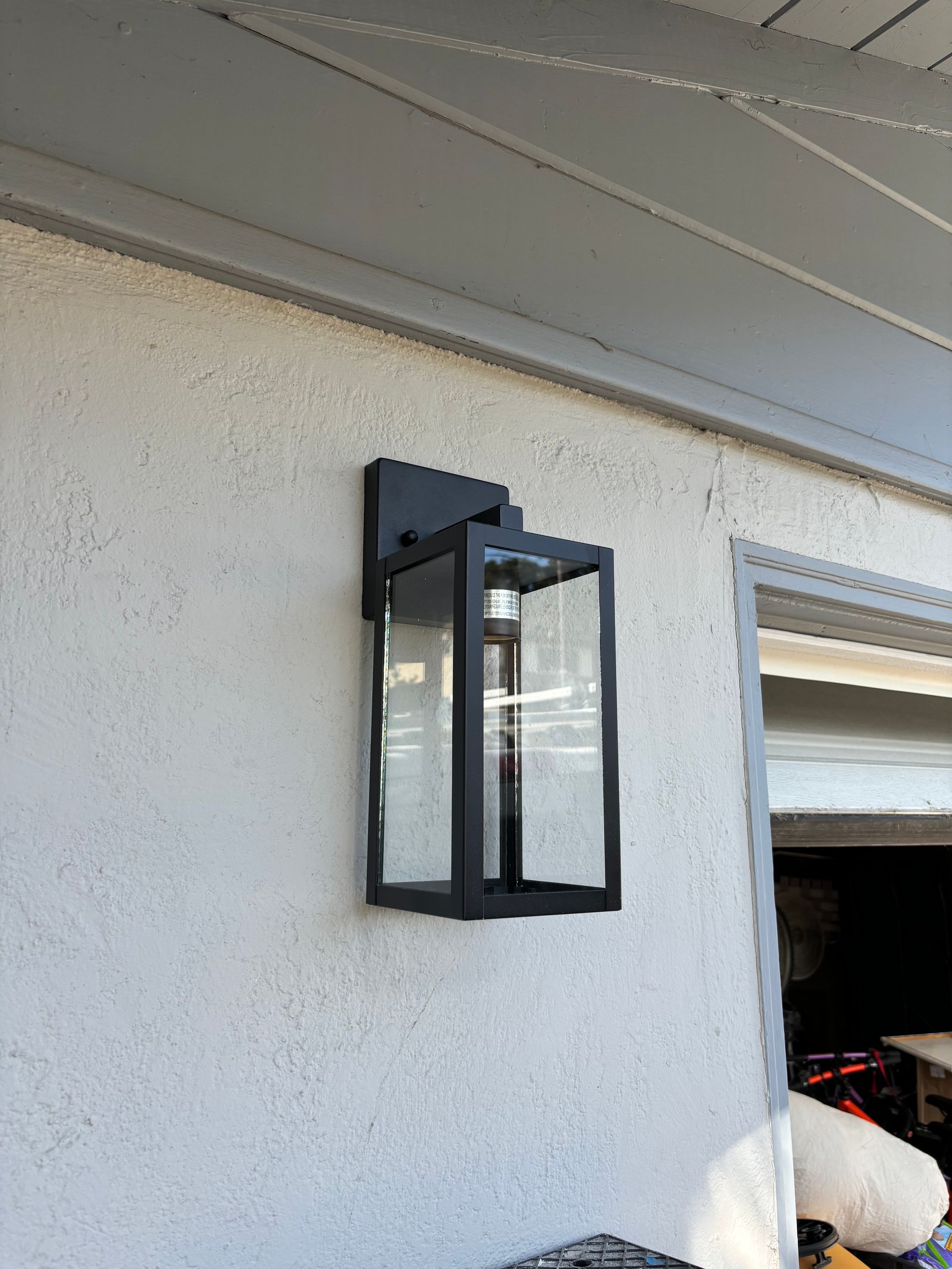 Black outdoor lantern on a stucco wall.