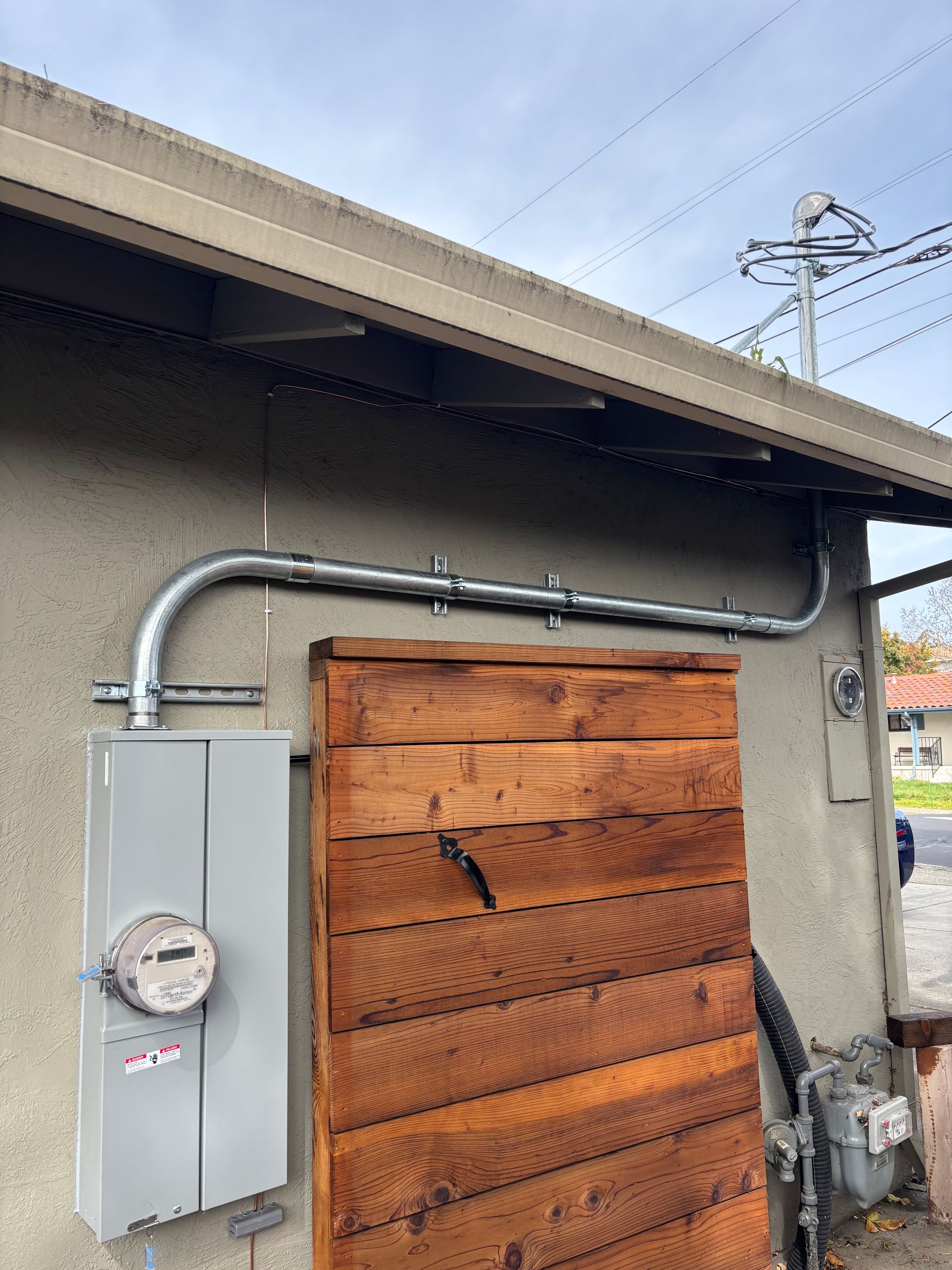Electrical conduit and meter box on a building wall next to a wooden door.