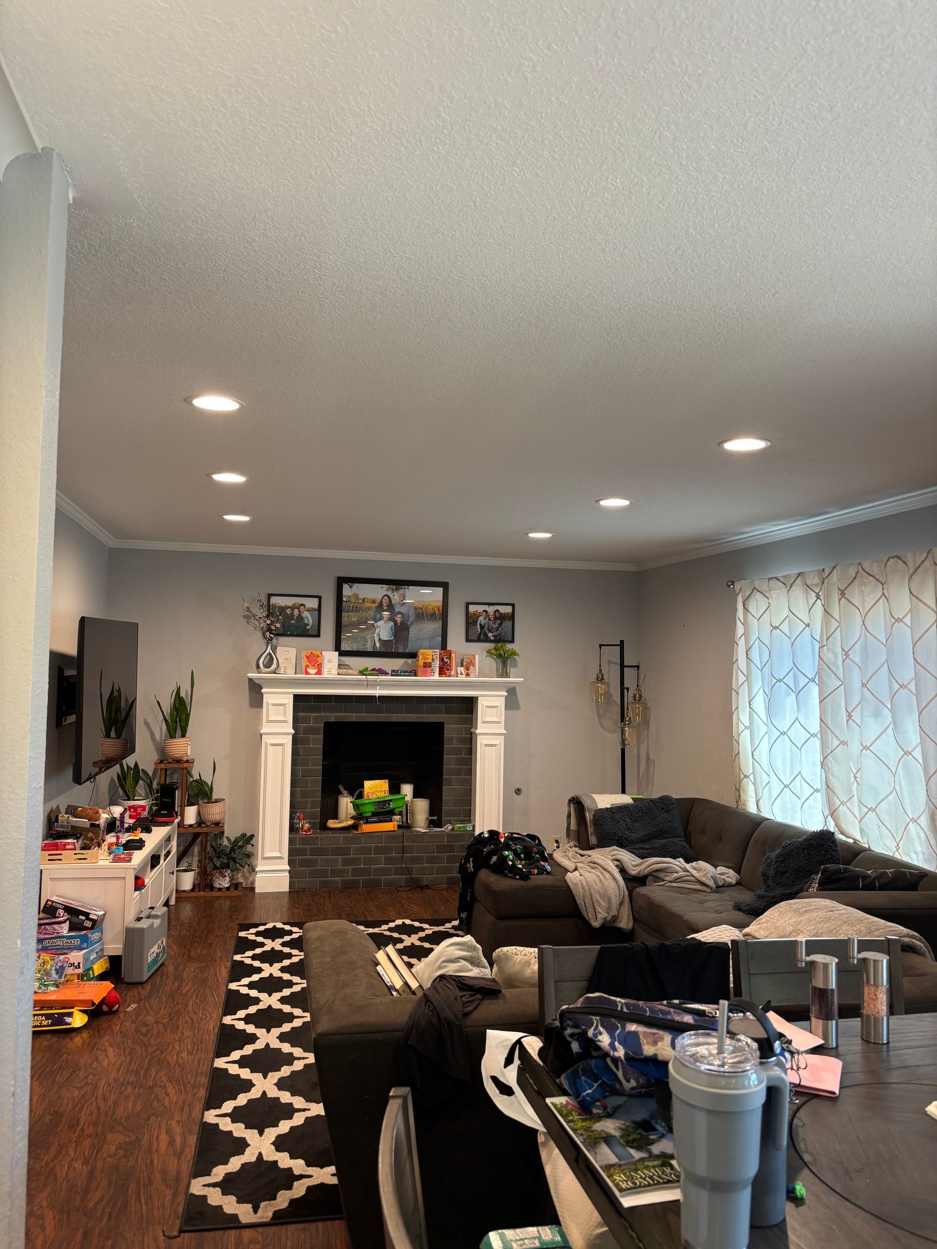 Living room with fireplace, sectional sofa, and recessed lighting. Dark rug, grey walls, and white trim.