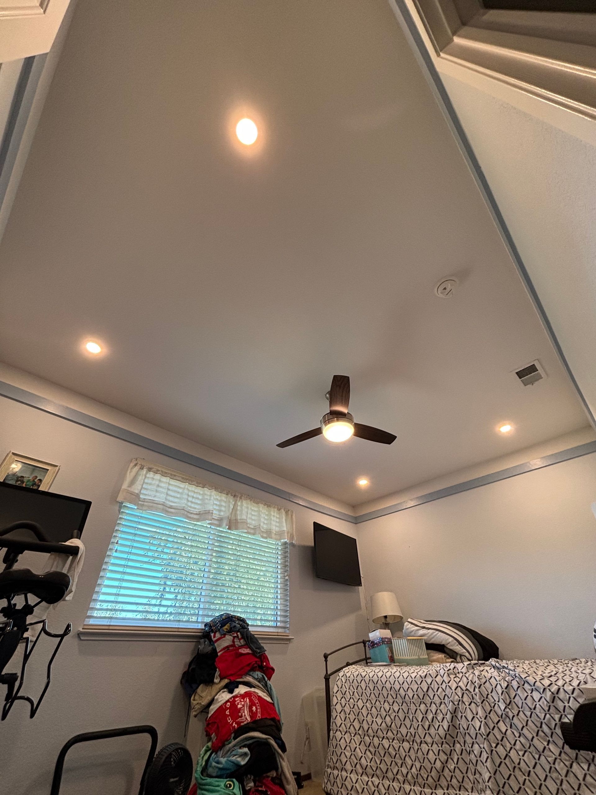 Bedroom ceiling with recessed lights, ceiling fan, window, and bed.