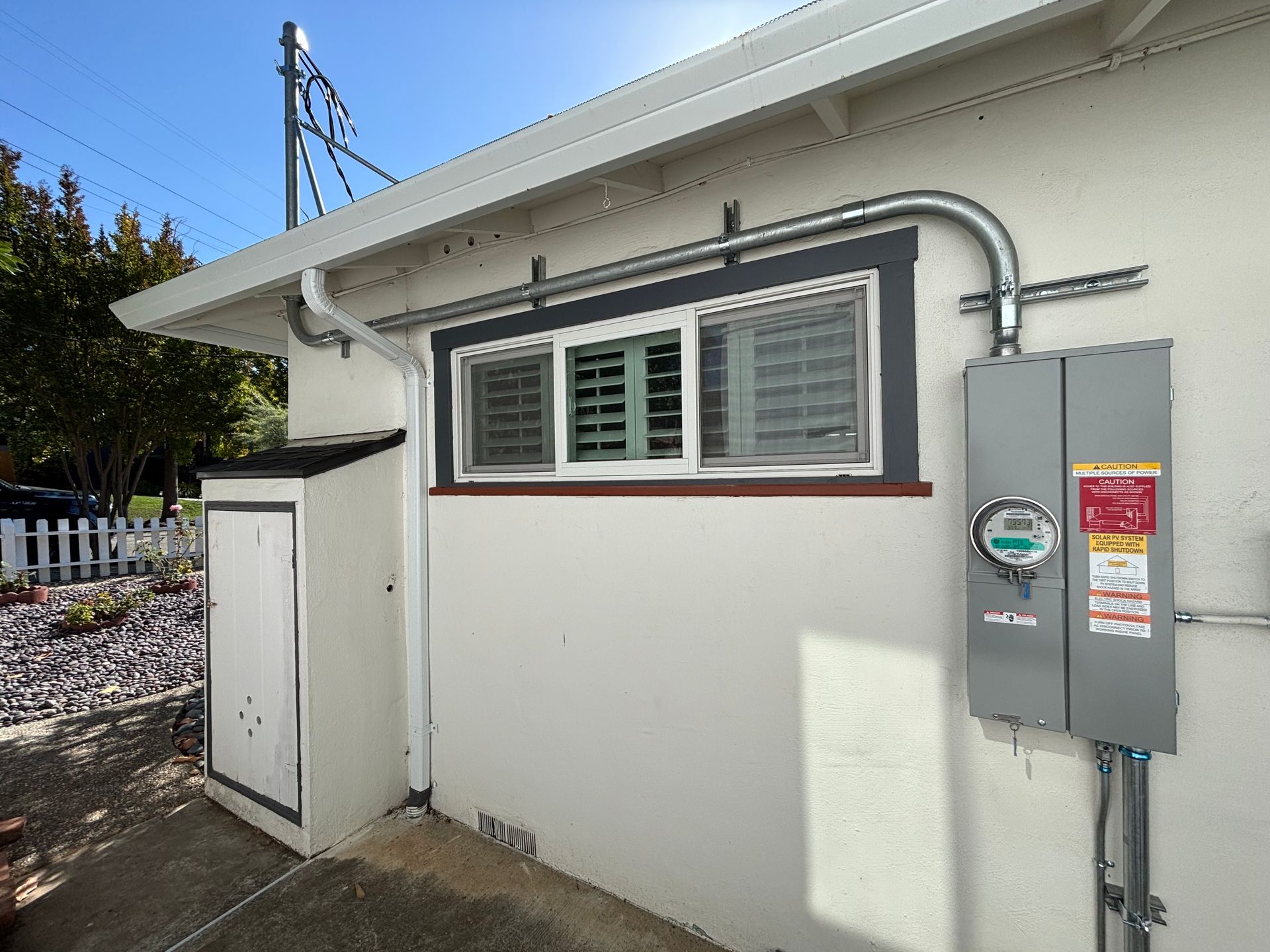 Exterior view of a house with a window, electrical meter, and conduit.