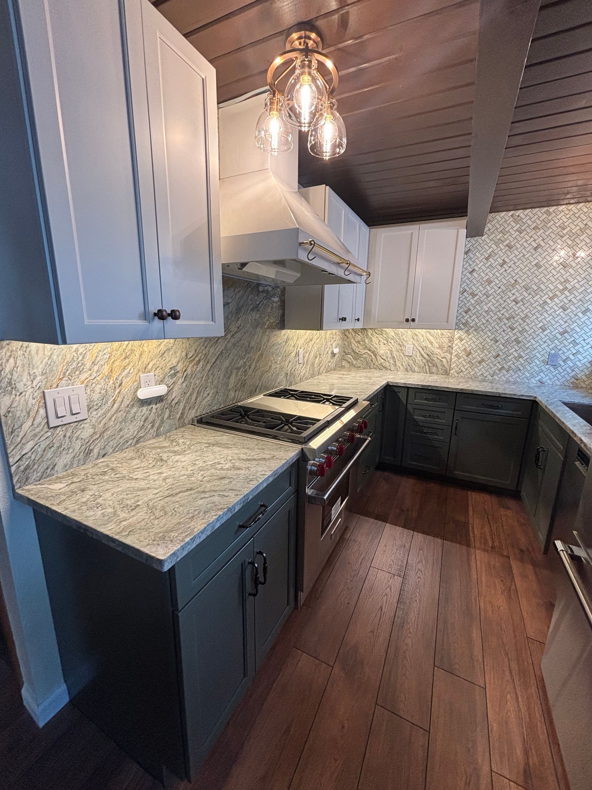 Kitchen with light gray cabinets, granite countertops, stainless steel appliances, and wooden ceiling.