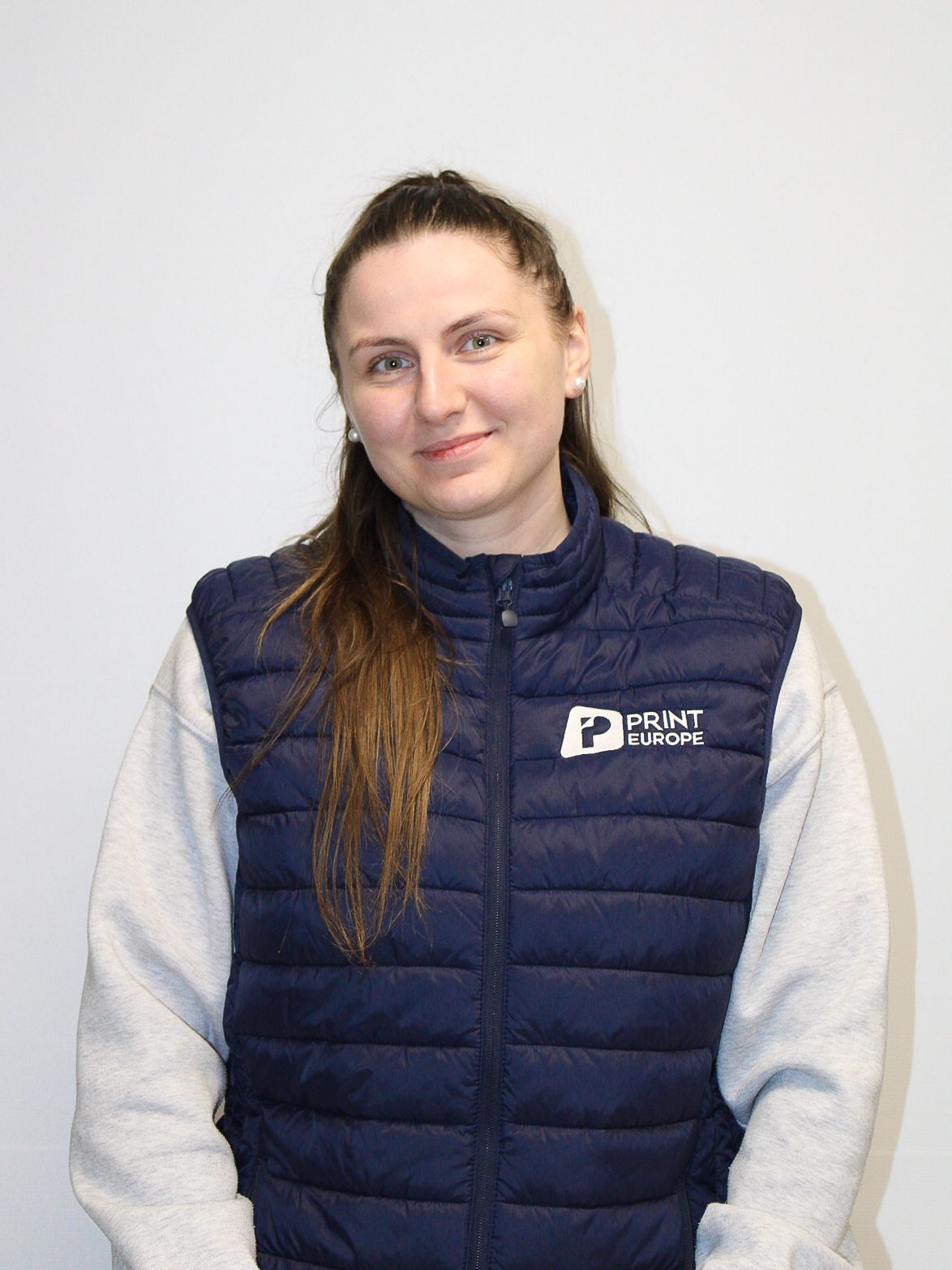 Une femme en chemise blanche pose pour une photo avec les bras croisés.