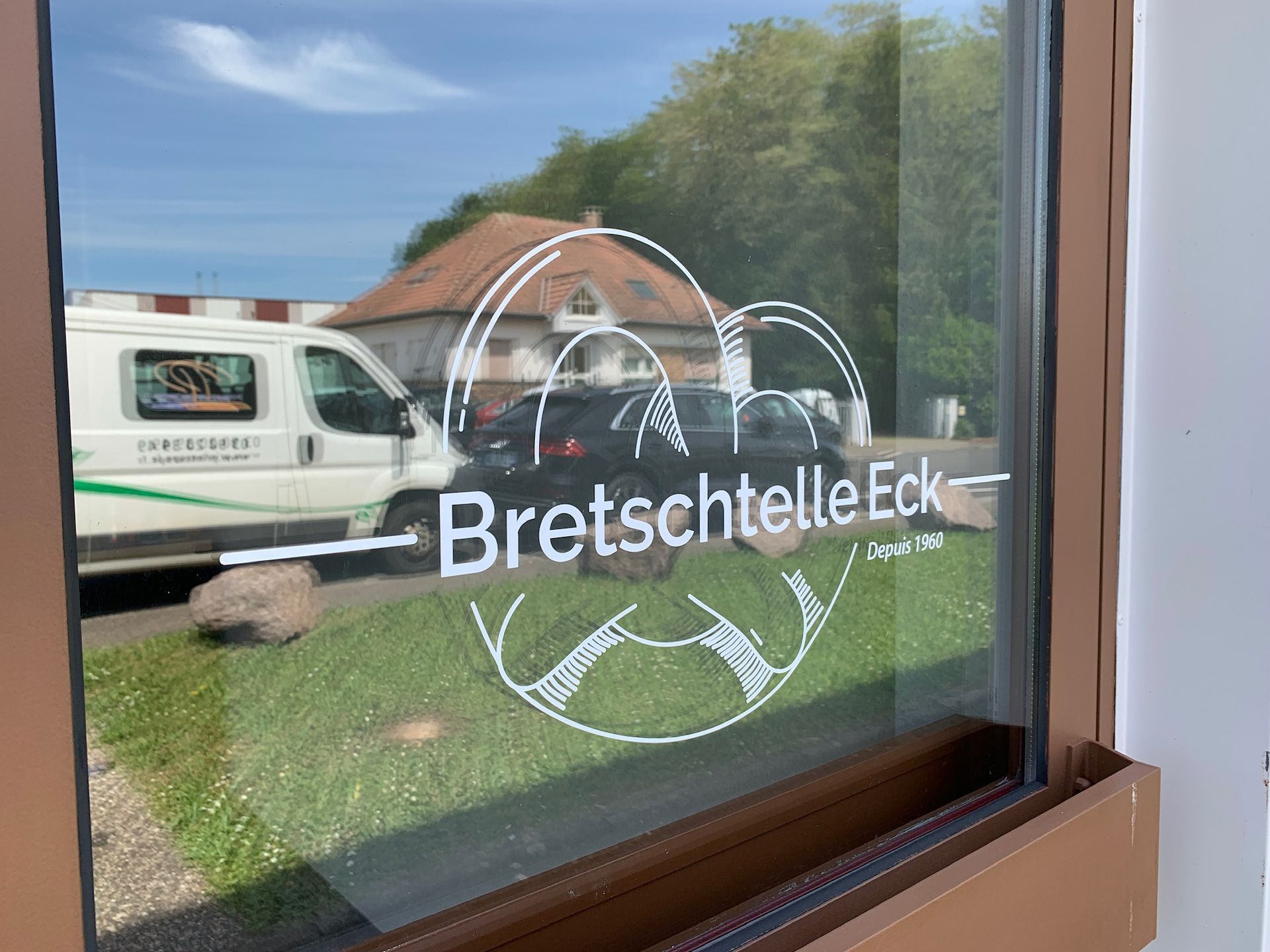 Une fenêtre avec un logo dessus et une camionnette en arrière-plan.