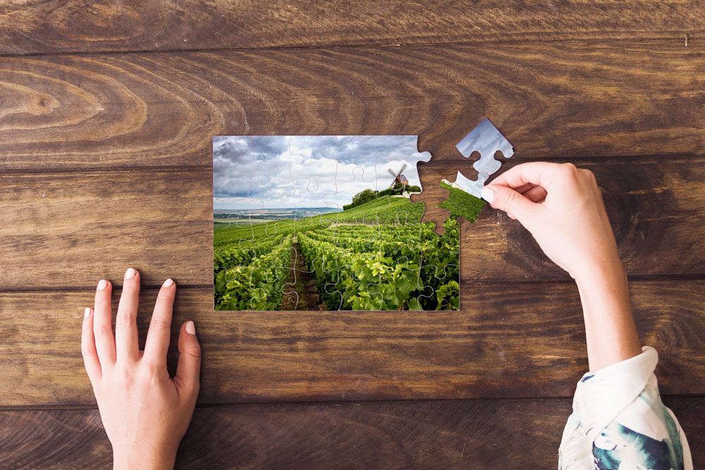 Une personne assemble une pièce d'un puzzle sur une table en bois.