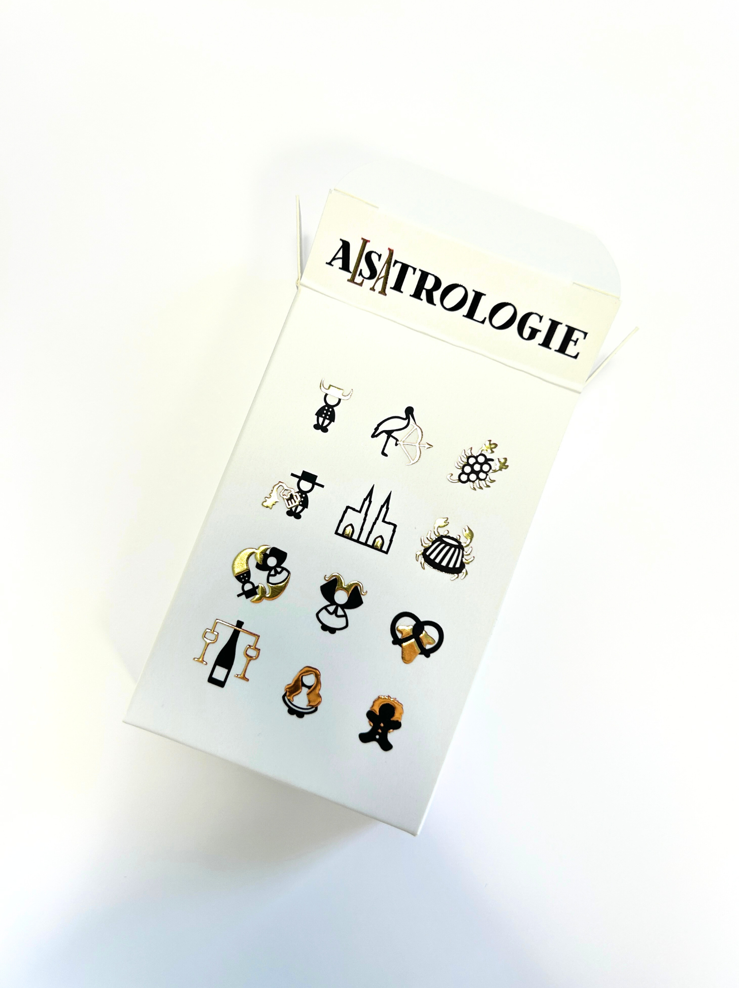 Une boîte de boucles d'oreilles avec différents motifs est posée sur une table.