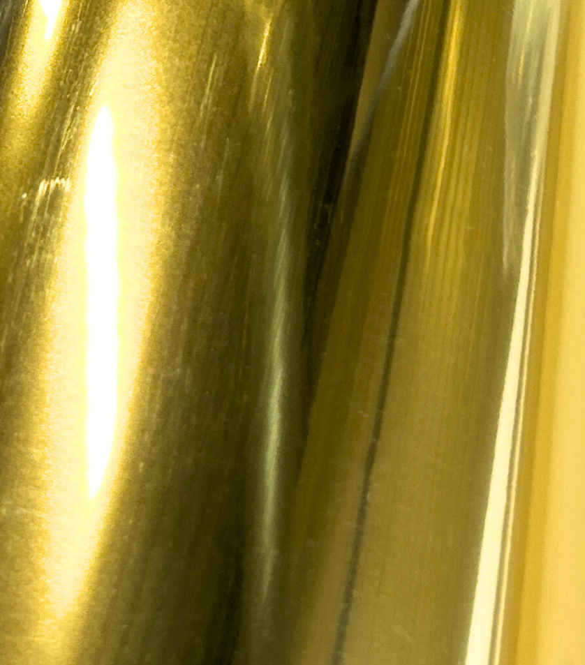Un gros plan d'un morceau de feuille d'or sur une surface blanche.