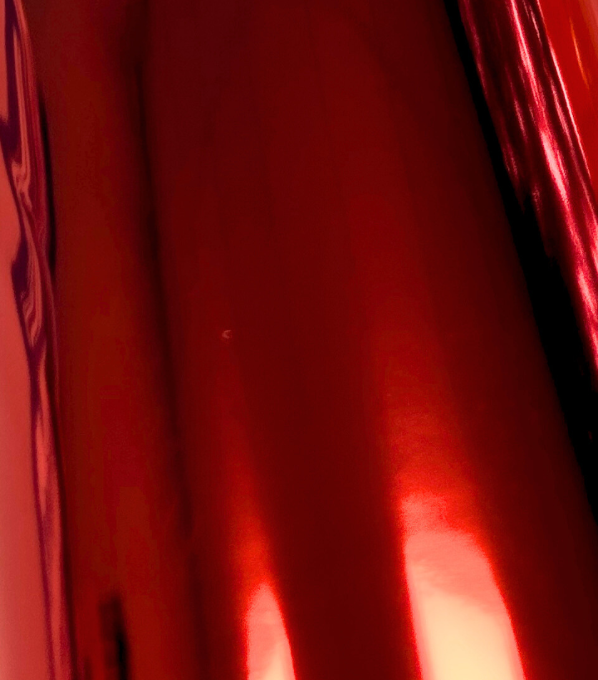 Un gros plan d'un rideau rouge avec une lumière qui brille à travers.