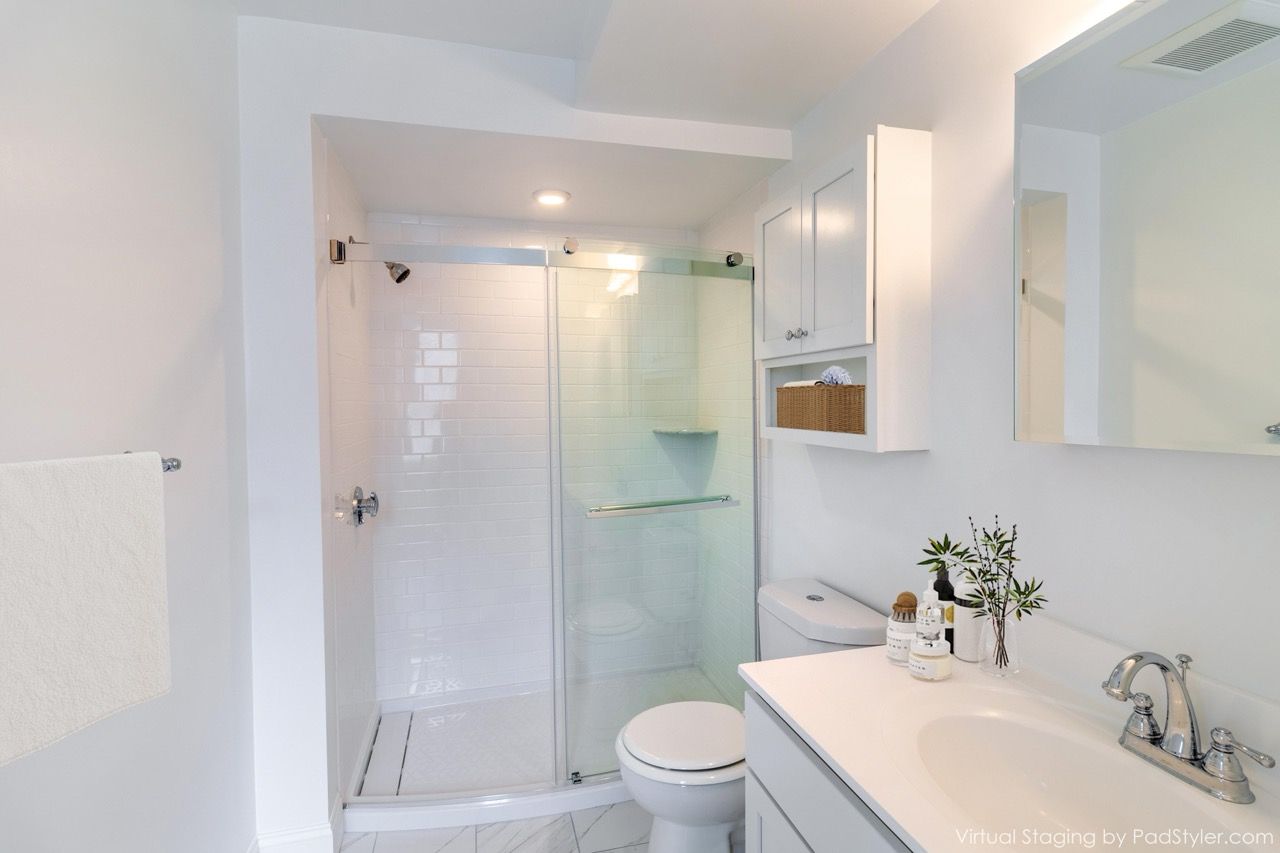 White bathroom with a glass sliding shower, toilet, and vanity.