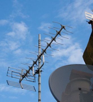 A satellite dish is attached to the side of a building.