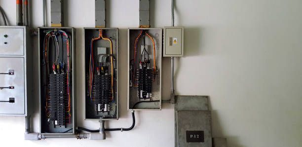 Electrical panel boxes mounted on a white wall with wiring and conduit visible.
