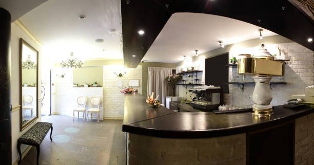 Interior of a cafe with a curved bar, stools, and chandelier lighting.