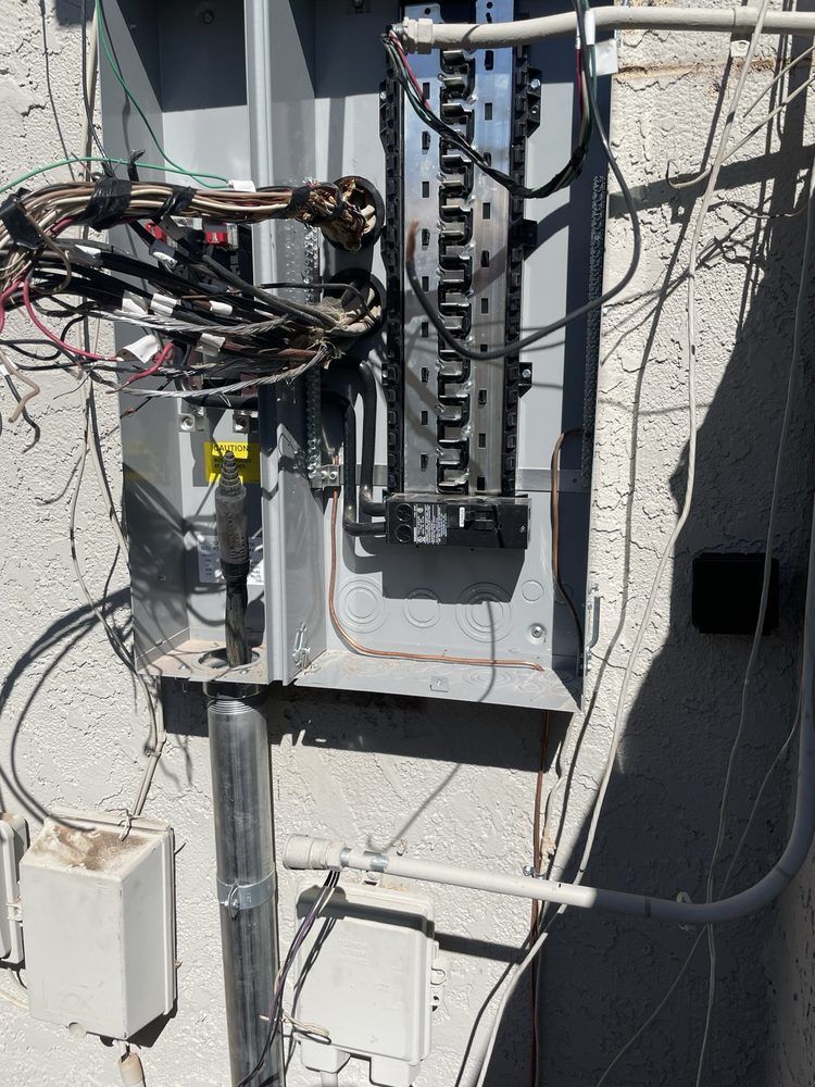 Electrical panel on an exterior wall with conduit and wiring.