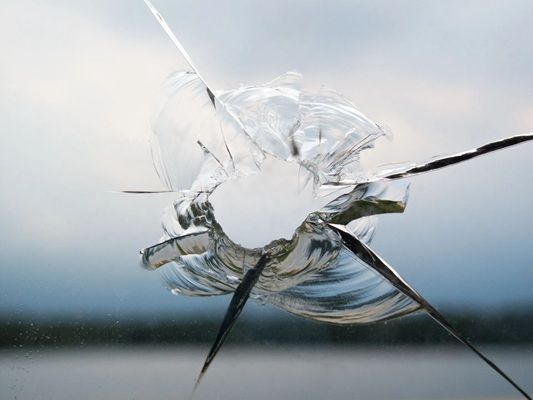 A close up of a broken glass window with a hole in it.